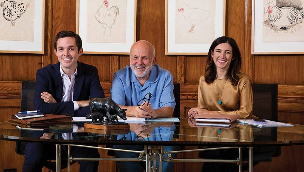 From left to right: John R. Tyson, John H. Tyson, and Olivia Tyson sit together in a board room.
