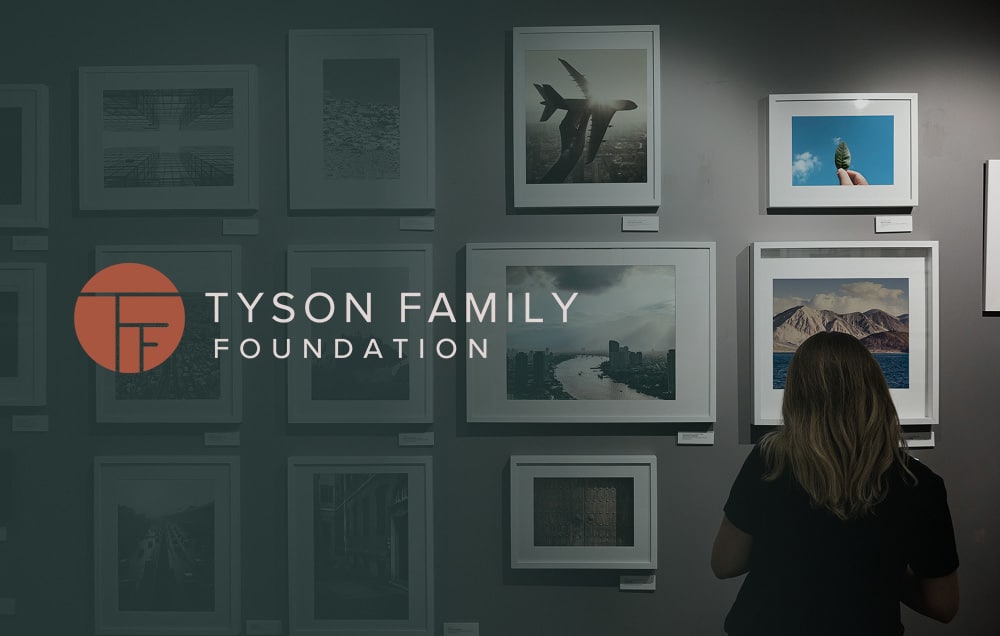 The Tyson Family Foundation logo imposed over a person looking at a picture wall.
